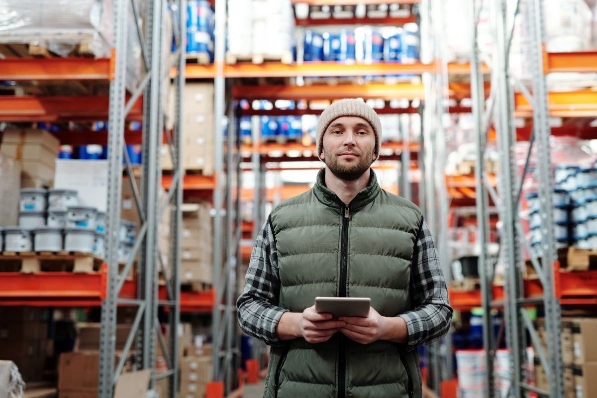 Warehouse worker using a tablet among stocked shelves