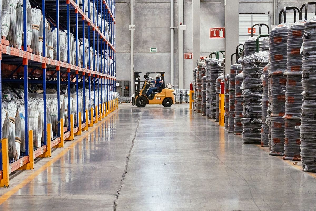 Forklift in a warehouse aisle with shelves of packaged goods