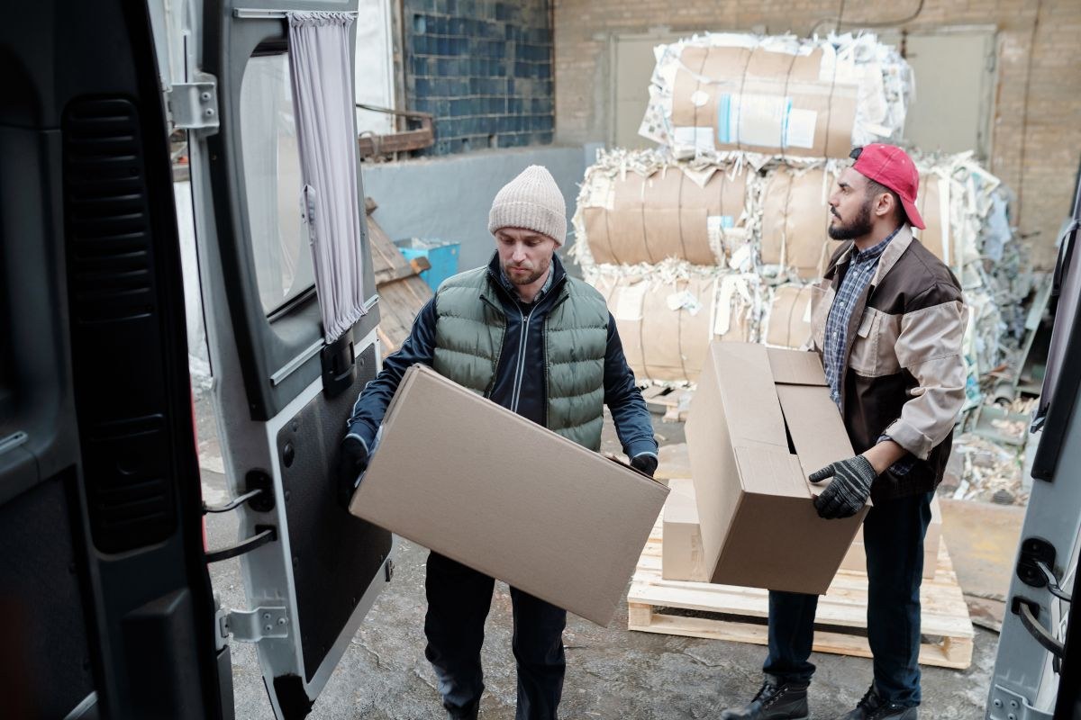 Two workers carrying cartons beside a delivery vehicle